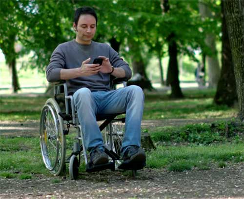 Gentleman in a wheelchair using a smartphone dating app in a park.